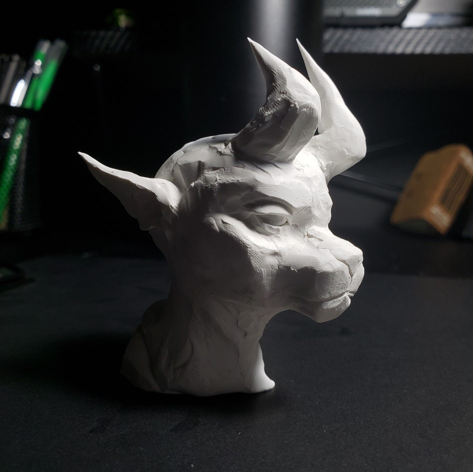 A small, desktop photo shoot of a sculpture of a demon character head.